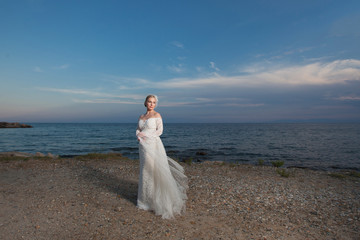 Fototapeta na wymiar Summer wedding. Beautiful bride on the sunset beach.
