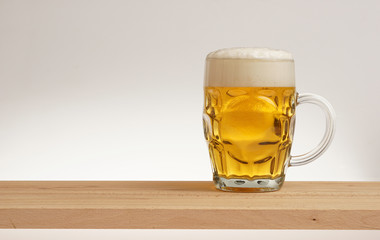 Glass of light beer on a wooden board.