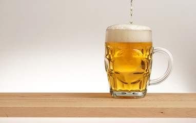 Glass of light beer on a wooden board.