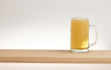 Mug of light beer on a wooden board.