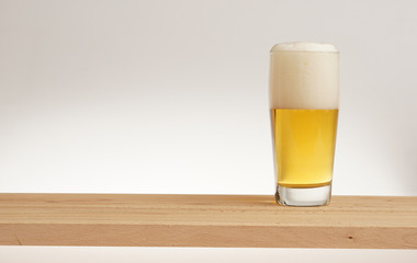 Glass of light beer on a wooden board.