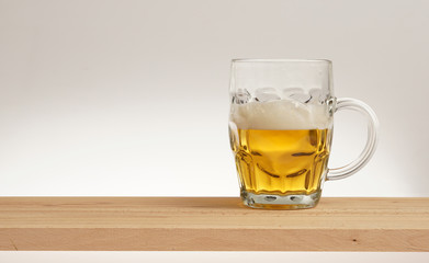 Glass of light beer on a wooden board.