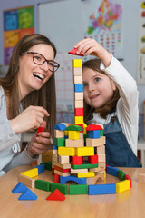 Mother and Daughter Playing Together with colorful building toy blocks. Support your child.
