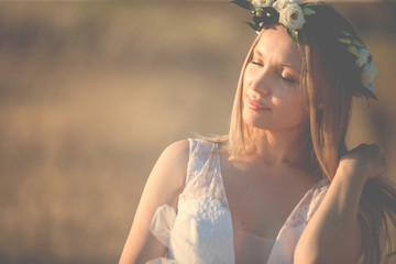 Portrait of beautiful romantic bride walking on summer sunset meadow
