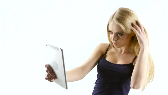 Cover girl makes selfie photos using the tablet. White studio