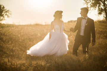 Young wedding couple enjoying romantic moments outside on a summer meadow. Happy groom and bride...