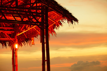 Tropical island grass hut against a beautiful sunset. 