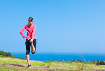 Female runner doing front thigh leg stretch.