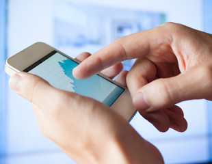 Man checking stock market chart with his smartphone.