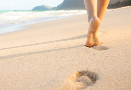 Tropical vacation concept. Closeup of woman's feet walking on the beach.