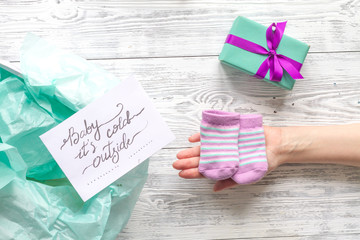 baby's bootees and gift box on wooden background