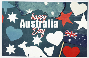 Celebrate Australia Day holiday on January 26 with a Happy Australia Day message greeting written across white Australian maps (red heart) and flag hanging pegs on blue background. Toned collage