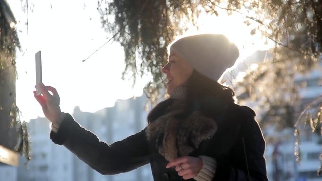 cheerful girl makes selfi during sunset in winter city