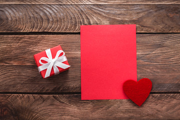 Valentines day greeting card and small gift, heart decoration over wooden background. Top view with copy space