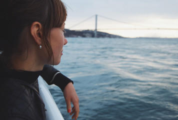 Young woman looking away from boat passing bridge