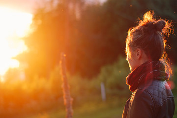 Young woman looking at glowing sunset flare