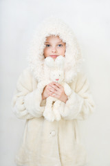Obraz premium Beautiful little girl in winter clothes with a toy rabbit.