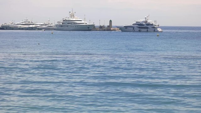 Water and yachts at daytime. Boats near lighthouse. Travel on elite private yacht.