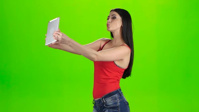 Brunette making photo using a tablet pc. Green screen studio