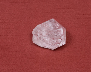 Rose quartz gemstone on red fabric background