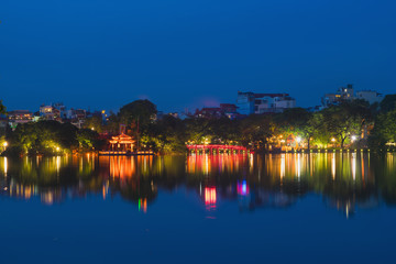 Fototapeta na wymiar Hoan Kiem lake view at twilight with Ngoc Son old temple and The Huc bridge. Hoan Kiem lake (Sword lake or Ho Guom) is center of Hanoi