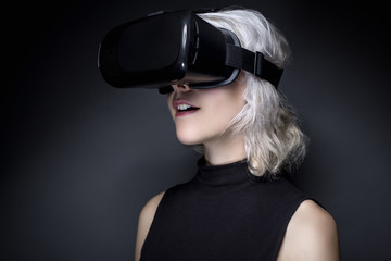 Woman wearing a futuristic looking virtual reality headset goggles.  The device is technology that...