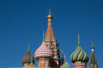 Fototapeta na wymiar St. Basil's Cathedral close up showing decorative and colorful onion domes topped with Orthodox crosses against a deep blue sky.