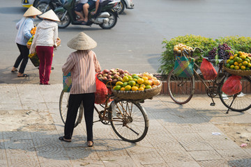 Fototapeta na wymiar Vietnamese vendors with tropical fruit loaded basket on bike