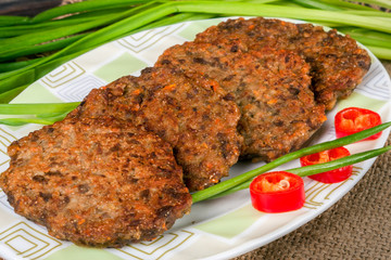 liver pancakes or cutlets with chili pepper and green onions on a wooden background