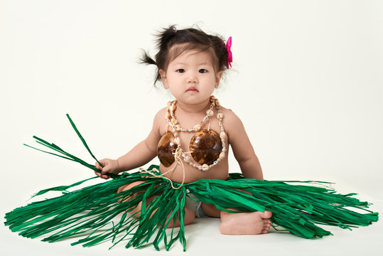 Cute Asian Chinese baby girl dressed in Hawaiian outfit.