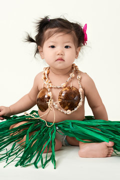 Cute Asian Chinese baby girl dressed in Hawaiian outfit.