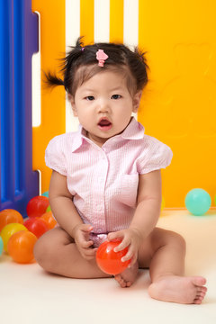 Asian Chinese Baby Girl Playing With Colorful Balls Fenced.