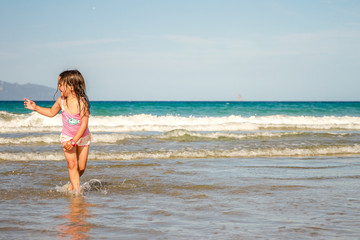 Fototapeta na wymiar young happy child girl having fun on sand beach, sea background