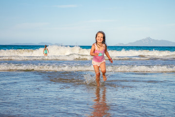 young happy child girl having fun on sand beach, sea background