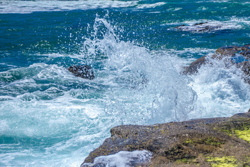 The waves breaking on a stony beach, forming a spray