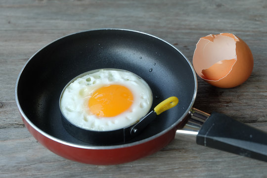 fried egg with pan on wood floor