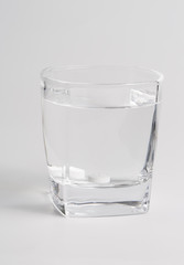White pills in a glass cup of water, closeup.