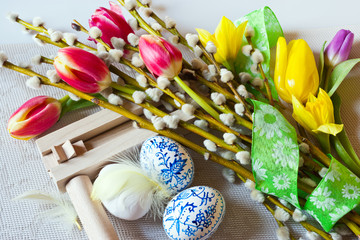 Traditional Czech easter decoration - regional wooden ratchet instrument with painted blue eggs with pussycats and tulips flower. Spring easter holiday arrangement.