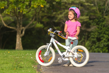 Obraz premium outdoor portrait of young happy child girl riding a bike in park