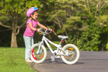 Fototapeta premium outdoor portrait of young happy child girl riding a bike in park