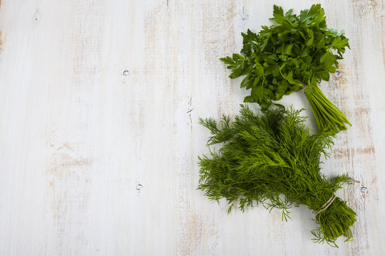 Dill and parsley on a light wooden table. Herbs closeup.