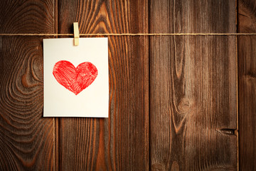 Card to day of St. Valentine and red heart on wooden
