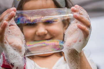 outdoor portrait of young happy child playing with soap bubbles