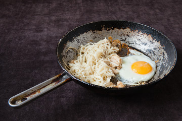 an old cast-iron frying pan with egg, pasta and fish