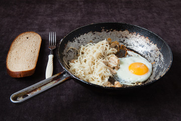 an old cast-iron frying pan with egg, pasta and fish