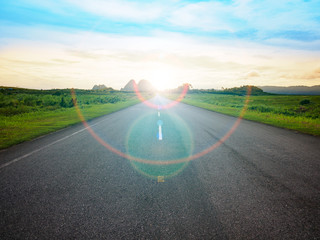 asphalt road with yellow blue sky background and Lens Flare or sunspot during sunset