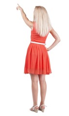 Back view of young blonde woman pointing at wall.