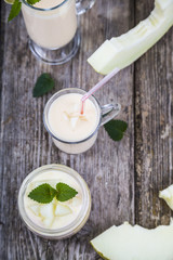 Yogurt and smoothie with melon on a wooden table.