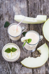 Yogurt and smoothie with melon on a wooden table.