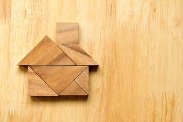 Tangram puzzle in home shape on wooden background (Concept for d